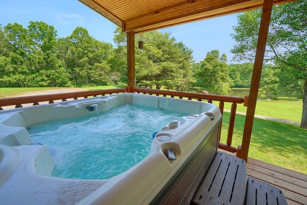 Un bain à remous sous une pergola en bois, avec vue sur un paysage verdoyant.