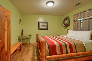 Une chambre avec un lit en bois, un bureau vert et un banc en bois.