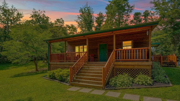 A wooden cabin with a porch, steps, and a green door.