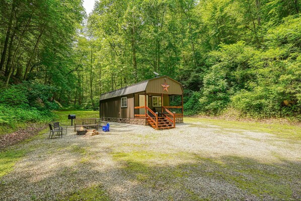 A cabin with a porch, a fire pit, and a mailbox.