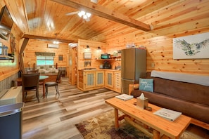 Interior acogedor de una cabaña con comedor, cocina y sala de estar.