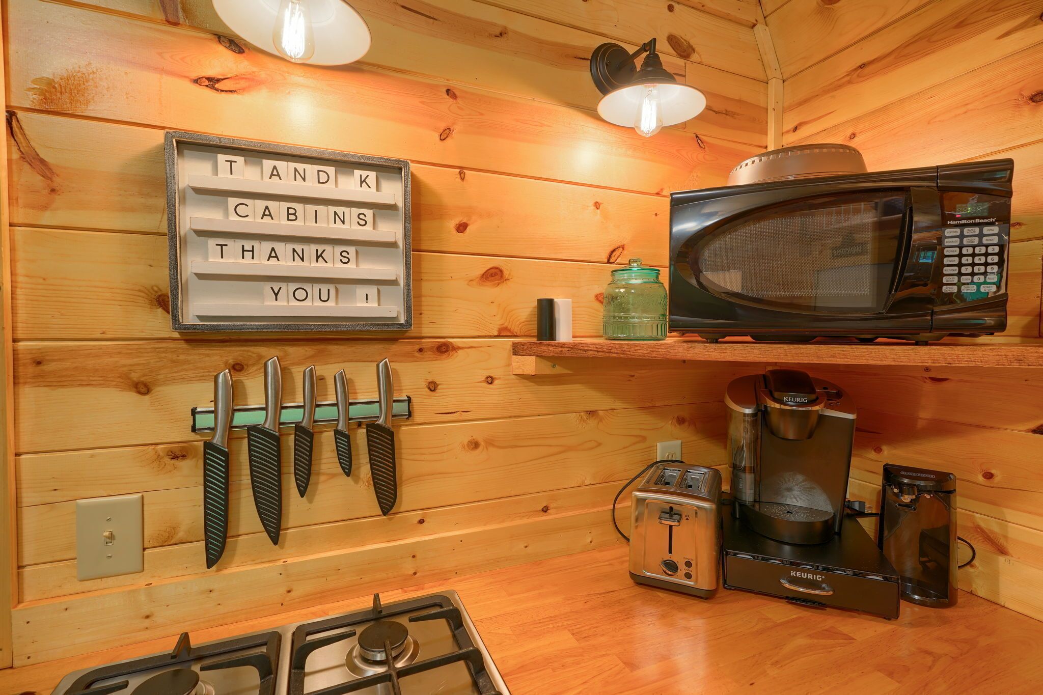 A kitchen with a microwave, toaster, coffee maker, and a sign that reads "THANKS YOU".