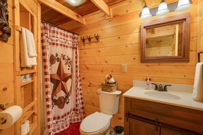 Ein Badezimmer einer Holzhütte mit Toilette, Waschbecken und Duschvorhang.