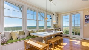 Une cuisine spacieuse avec de grandes fenêtres, une table à manger en bois et un banc.