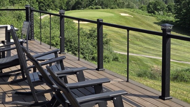 Terraza de madera con sillones de descanso con vista a un campo de golf y un cuerpo de agua.
