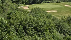 Campo de golf con vista despejada al océano y bosque denso.
