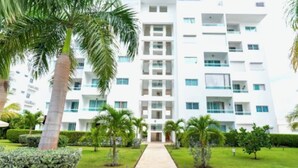 A modern multi-story hotel with a central courtyard, surrounded by palm trees and well-maintained greenery. - Charming, elegant 2-bedroom condo with WiFi, AC in delightful Playa Juan Dolio (Playa Juan Dolio)
