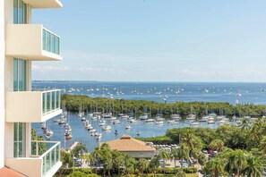 A marina with numerous sailboats docked, surrounded by lush greenery and a clear sky.