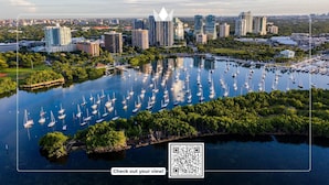 Un port de plaisance où sont amarrés de nombreux voiliers, entouré d’une végétation luxuriante et avec une vue sur la ville en arrière-plan.