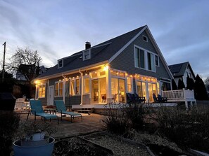Et toetagers hus med en overdækket terrasse, store vinduer og en træterrasse.