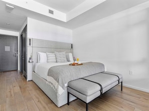 A modern bedroom with a bed, bedside table, and a bench. - Modern Downtown Residence | Walk to Everything (Miami)
