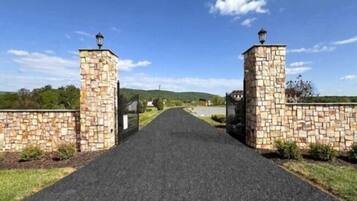 A paved pathway leading to a gated entrance with stone walls and lanterns.