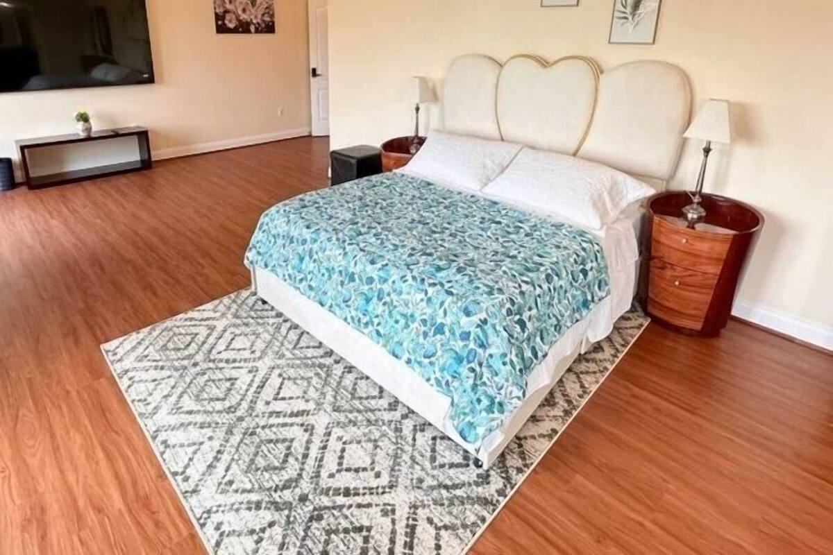 A bedroom with a bed, a TV, a bedside table, and a lamp.
