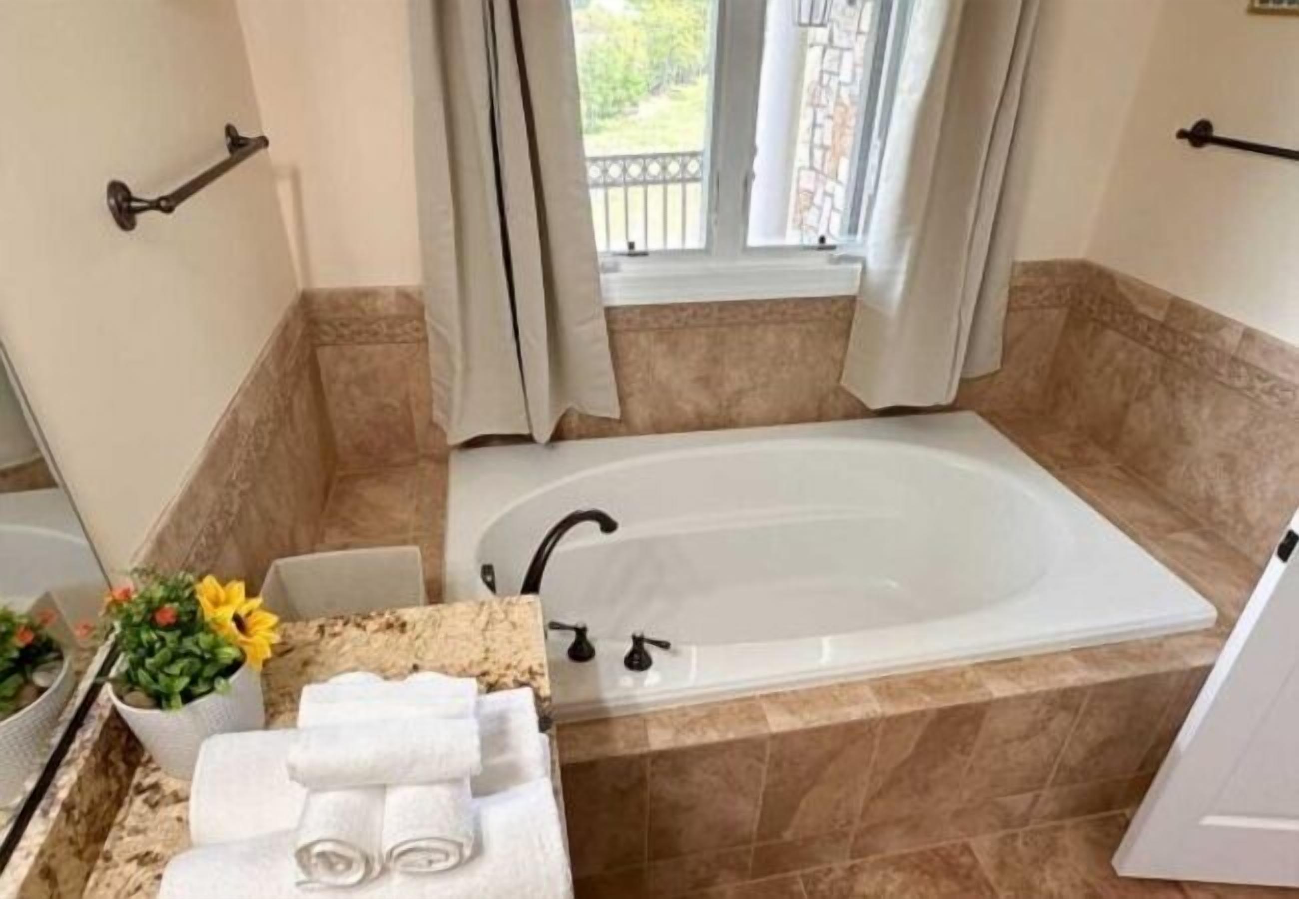 Un baño con bañera, lavamanos y ventana con cortinas.