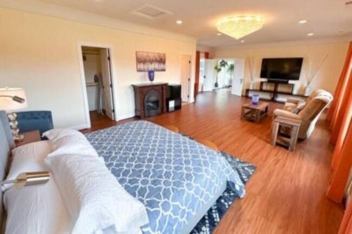 A spacious hotel room with a large bed, a television, a fireplace, and a seating area with a coffee table.