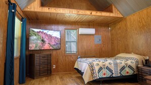 Una stanza accogliente in legno, con un letto, una televisione e una finestra.