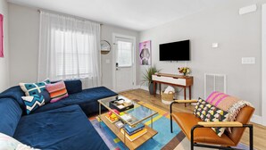 A modern living room with a sofa, armchair, coffee table, and a flat-screen TV. - Optimist Abode 1: Chic Stay on Greenway, less than 7 min to NoDa-Midwood-Uptown (Charlotte)