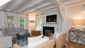 Una sala de estar acogedora con chimenea, asientos cómodos y un amplio ventanal.