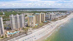 A coastal resort with high-rise buildings, a beach, and a water tower. - Beach Colony Tower 1B (Pensacola)