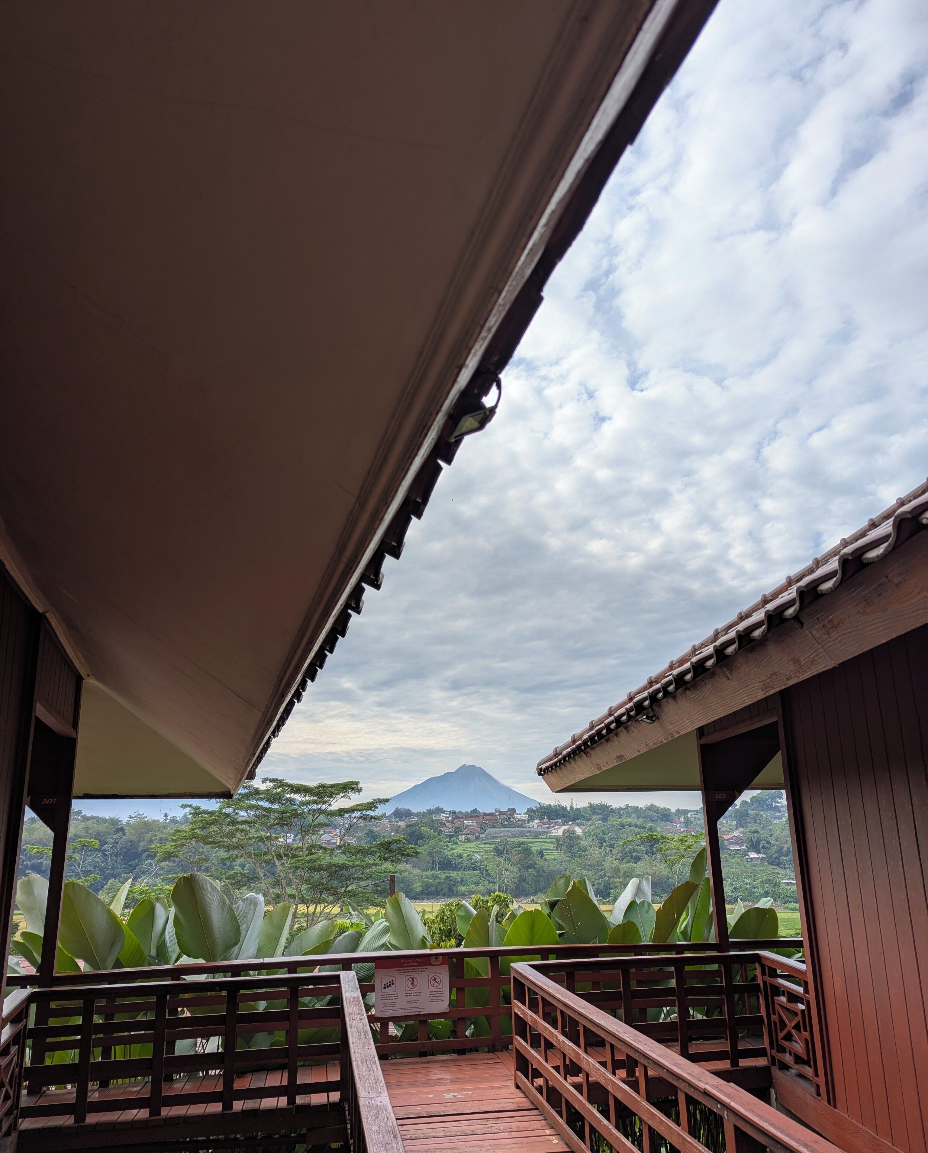 A wooden deck with a view of a mountain and lush greenery.