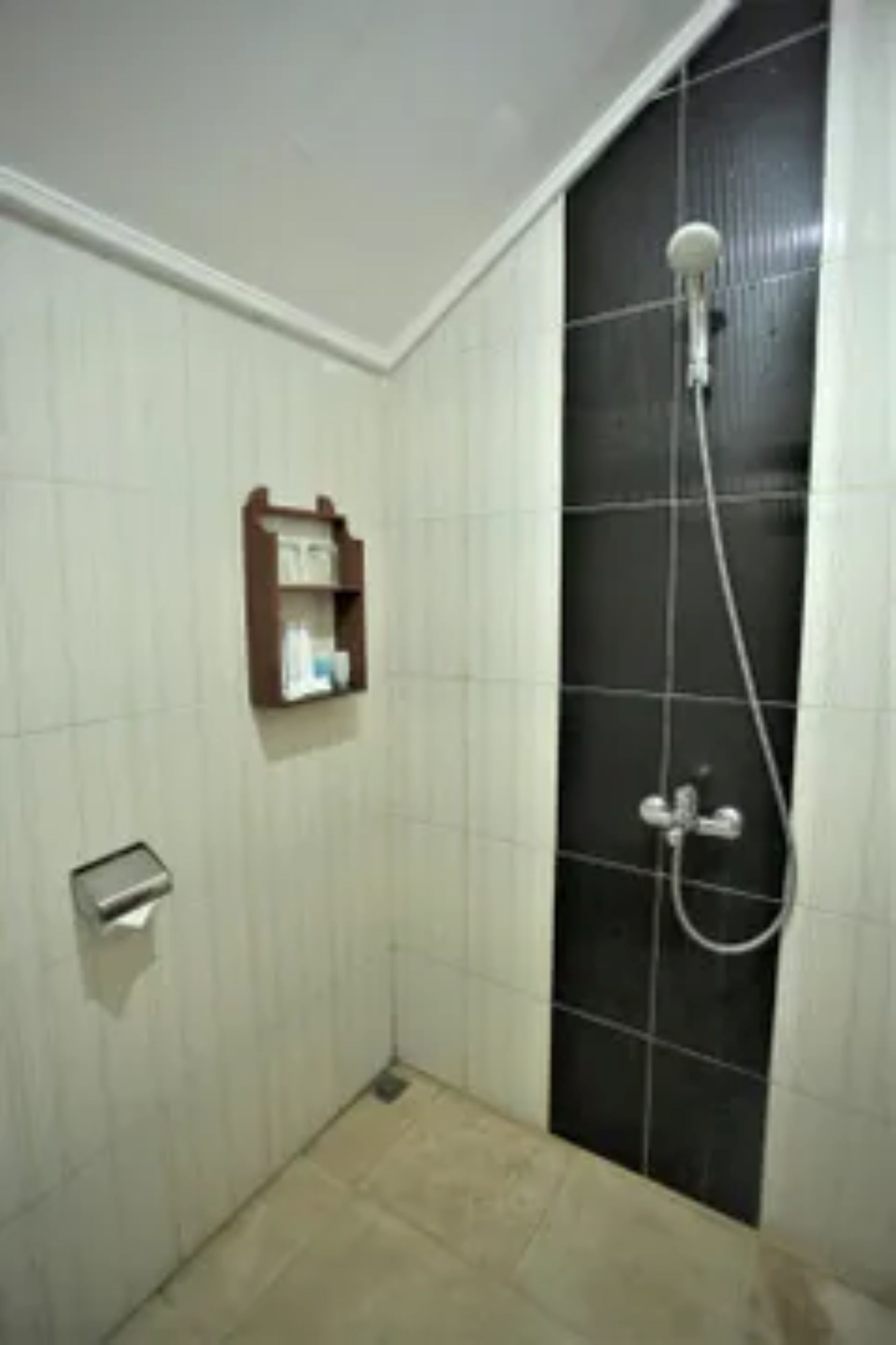 Un espacio de ducha pequeño con azulejos, un cabezal de ducha manual y un grifo empotrado en la pared.