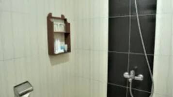 Un espacio de ducha pequeño con azulejos, un cabezal de ducha manual y un grifo empotrado en la pared.