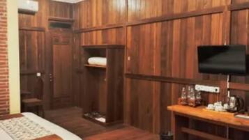Een hotelkamer met houten lambrisering, een bed, een bureau met televisie en een klein zitgedeelte.