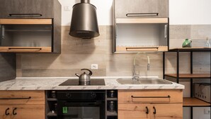 A modern kitchen with wooden cabinets, a built-in oven, a stainless steel sink, and a kettle on the countertop. - Borgo dei Cedri Apartment 2 by Wonderful Italy (Bari)
