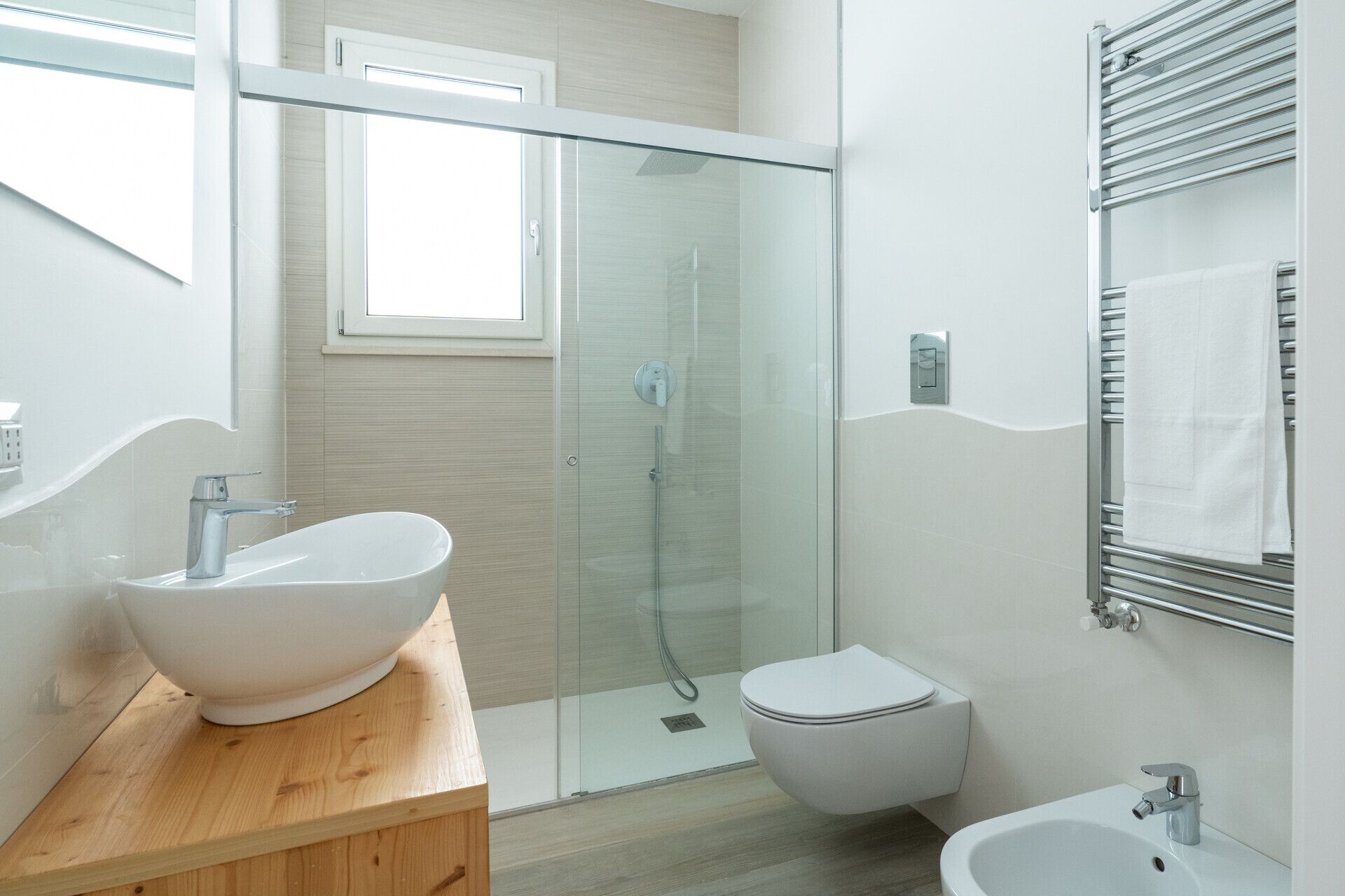 Une salle de bain moderne avec une douche à parois de verre, un lavabo blanc, des toilettes et un bidet.