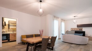 A modern kitchen with a built-in oven and a dining area with a wooden table and chairs. - Borgo dei Cedri Apartment 2 by Wonderful Italy (Bari)