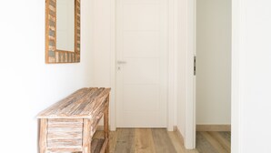 A hallway with a white door, a wooden bench, and a mirror with a rustic frame. - Borgo dei Cedri Apartment 2 by Wonderful Italy (Bari)