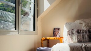 A room with a large window, a bed, a small table, and a cushion. - Idéal Cure thermale à Cauterets - Near thermal baths & town center, 32 m² T2 (Cauterets)