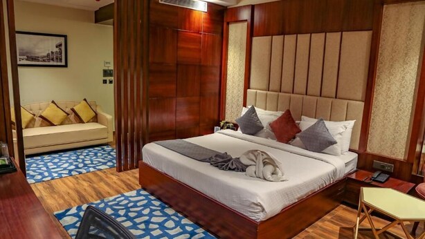 A hotel room with a large bed, a sofa, a desk, and a chair. - Four Leaf Hotel Akosha, Varanasi (Varanasi)