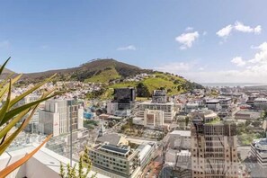 A cityscape with modern buildings, a hill in the background, and a clear sky. - The Rubik Deluxe Apartment (Cape Town)