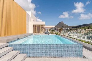A rooftop pool with a clear view of a mountain and cityscape. - The Rubik Deluxe Apartment (Cape Town)