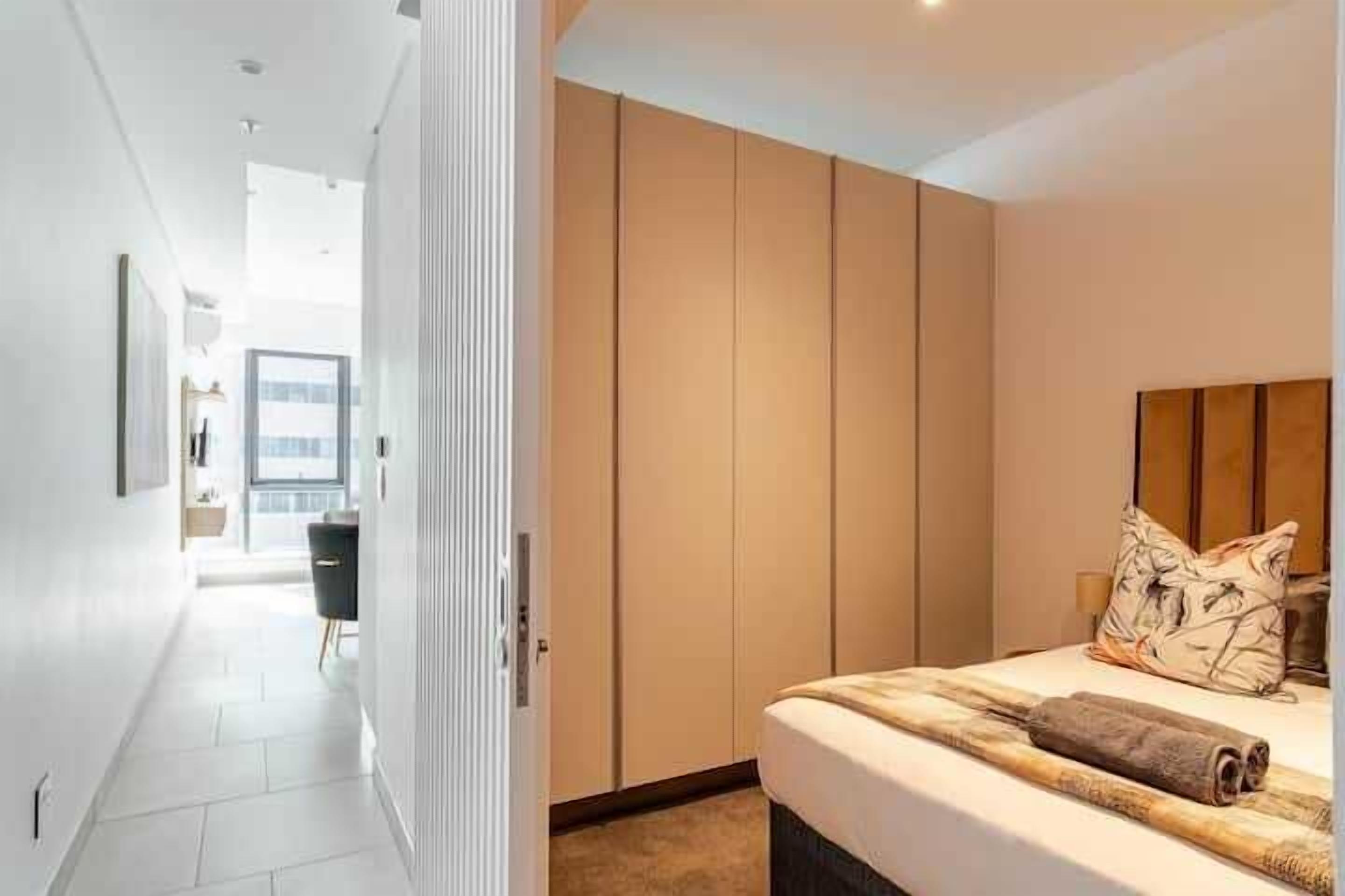 Un dormitorio moderno con una cama grande, cabecera y vistas a un balcón.