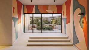Un interior moderno con una escalera que lleva a un vidrio, diseño minimalista y vista a un jardín exterior.