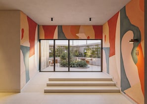 Un interior moderno con una escalera que lleva a un vidrio, diseño minimalista y vista a un jardín exterior.