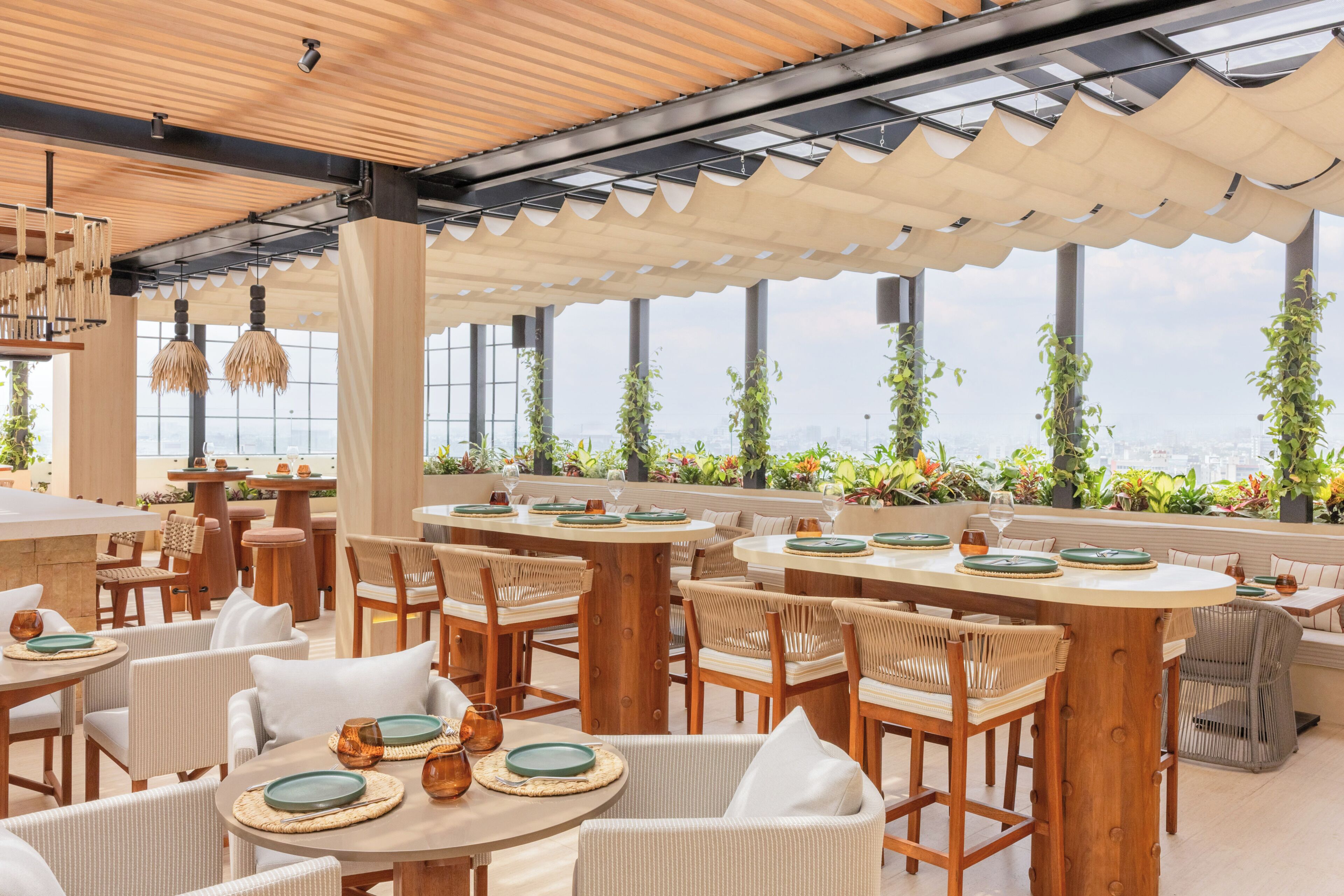 An outdoor dining area with round tables, wicker chairs, and a view of the city.