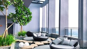 A modern outdoor lounge area with circular seating, a tree, and a view of the city.