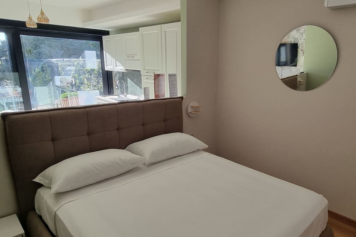 A bedroom with a large bed, a window, and a mirror on the wall.