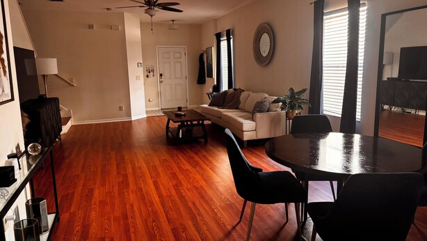 A spacious living room with hardwood flooring, a sofa, a coffee table, and a dining table with chairs. - 3-bedroom townhome in charming Riverview with WiFi, AC. Relax and unwind (Riverview)