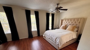A bedroom with a large bed, a ceiling fan, and windows with black curtains. - 3-bedroom townhome in charming Riverview with WiFi, AC. Relax and unwind (Riverview)