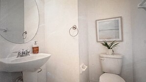 A bathroom with a sink, mirror, toilet, and a framed picture on the wall. - 3-bedroom townhome in charming Riverview with WiFi, AC. Relax and unwind (Riverview)