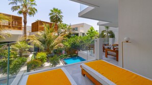 Une chambre d’hôtel moderne avec balcon, piscine et végétation luxuriante.