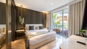 Une chambre d’hôtel moderne dotée d’un grand lit, de tables de chevet, d’un petit bureau et d’une grande fenêtre donnant sur l’extérieur.