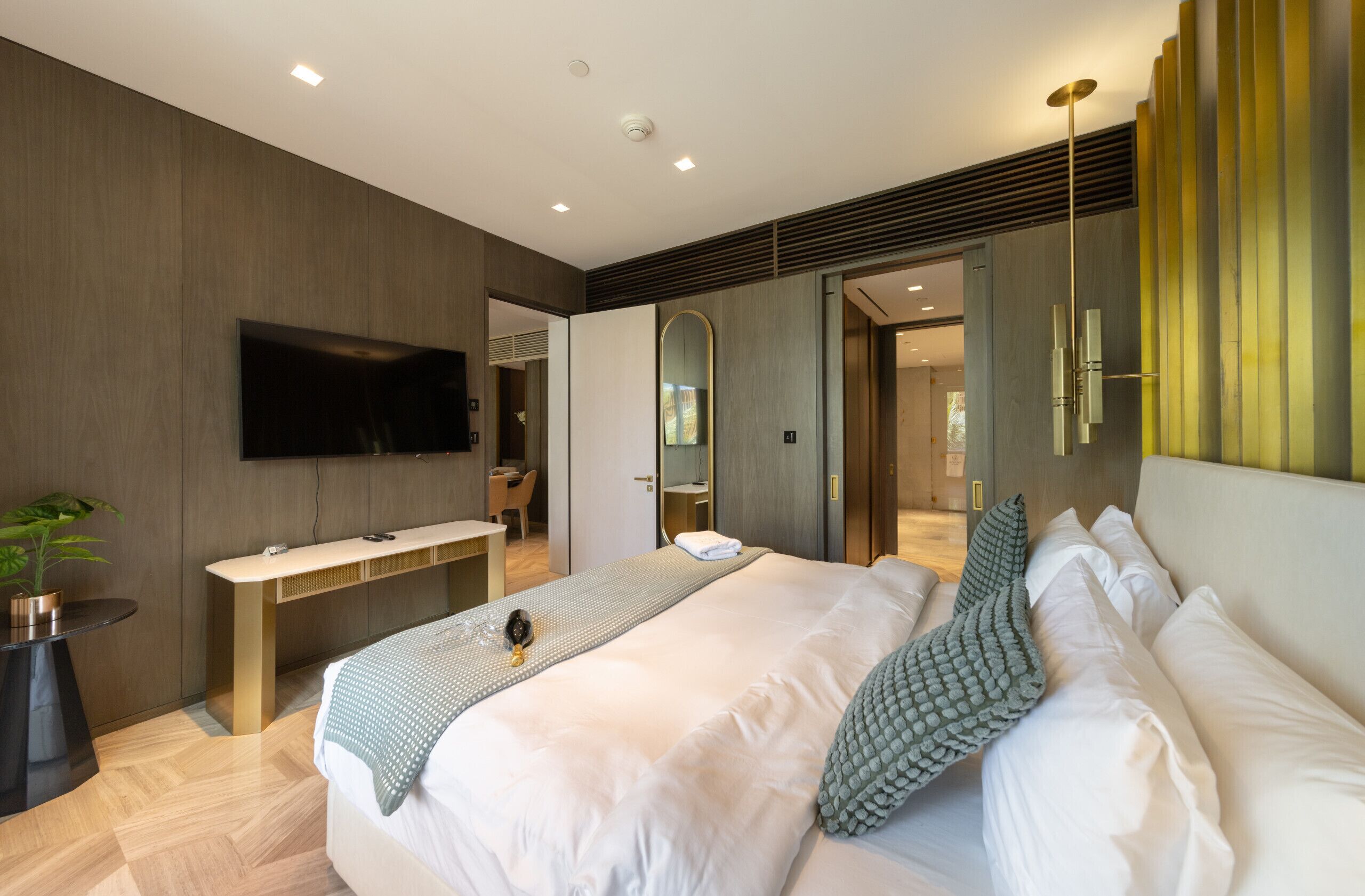 Een moderne slaapkamer met een groot bed, nachtkastje en een wandmontage flatscreen-televisie.
