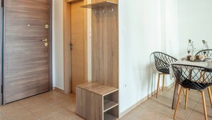 Ein modernes Zimmer mit Holztür, einem Schrank mit Sitzbank und einem Essbereich mit Stühlen und Tisch.