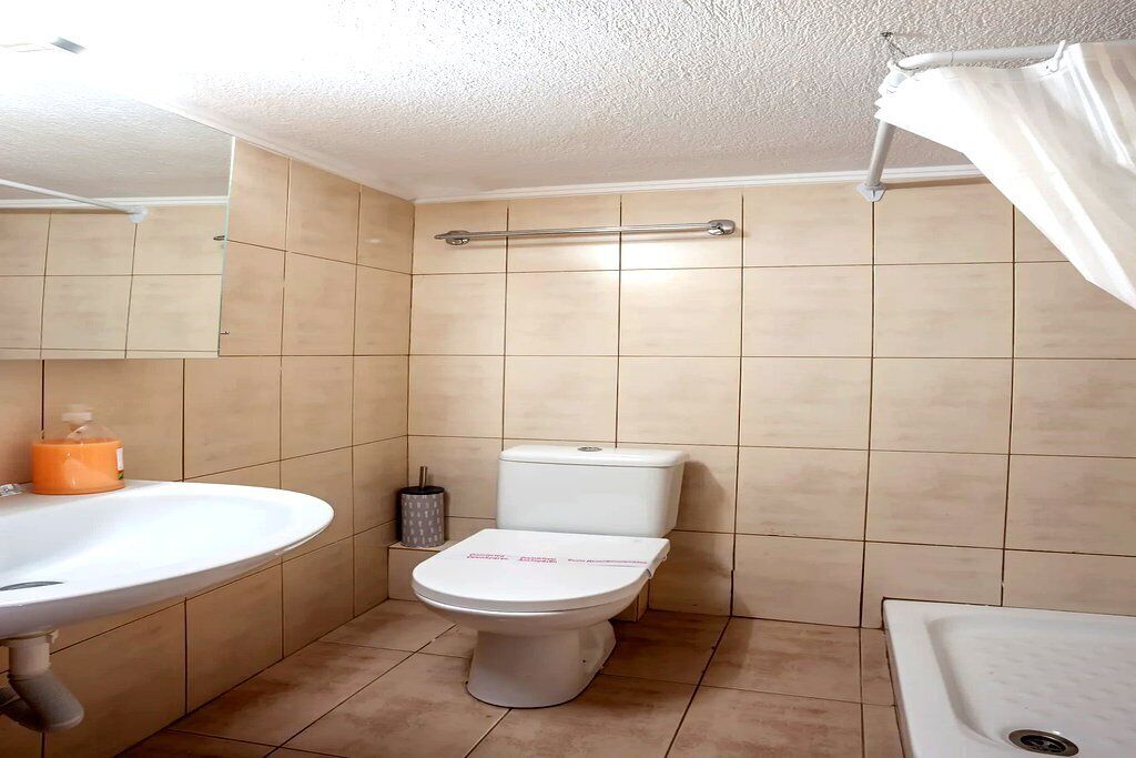 Et badeværelse med toilet, håndvask og bruseniche.