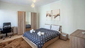 Ein Schlafzimmer mit Bett, Schreibtisch, Stuhl, Kleiderschrank und zwei Wandbildern.